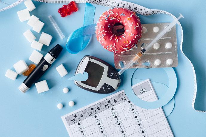 An image of glucometer with strips and donut on top of a table