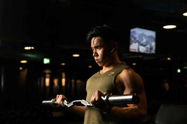 Een man die krachttraining doet met stalen buizen in de donkere sportschool