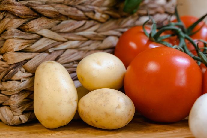 Uma foto de batata e tomate com uma cesta atrás