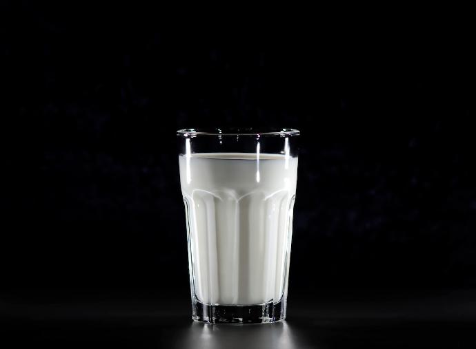 Een glas melk op zwarte achtergrond