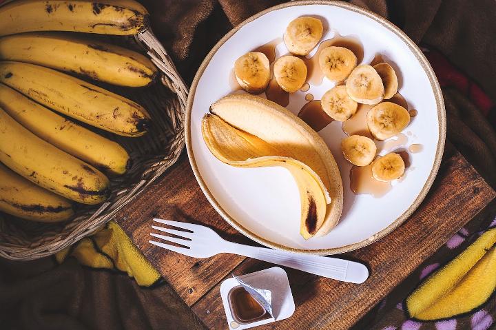 Bananenschil bovenop tafel met bord en honing