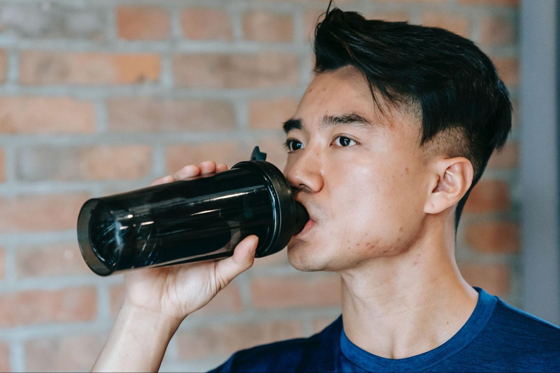 Um homem bebendo leite proteico em uma caneca preta