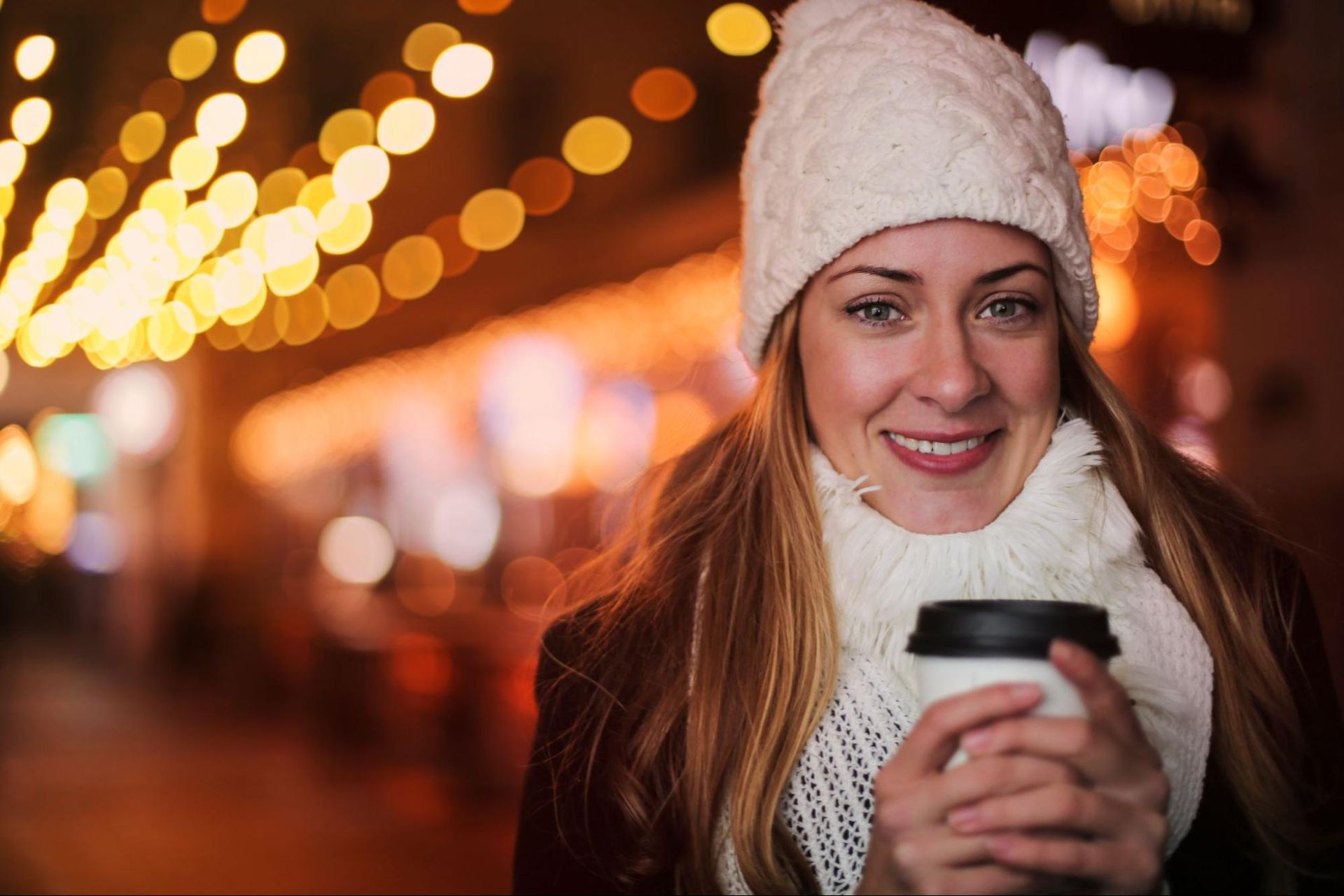 Uma garota segurando uma xícara de café com luzes bokeh como fundo