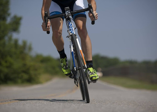 A cyclist biking in the road with green rubber shoes