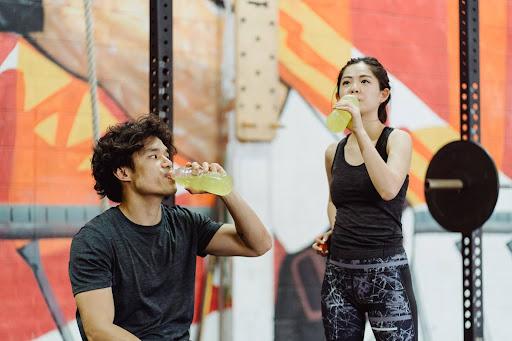 Un uomo e una ragazza che si idratano dopo l'esercizio in palestra