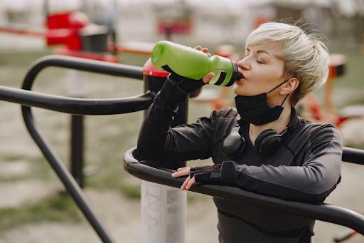 Une fille boit de l’eau pour s’hydrater dans un parc