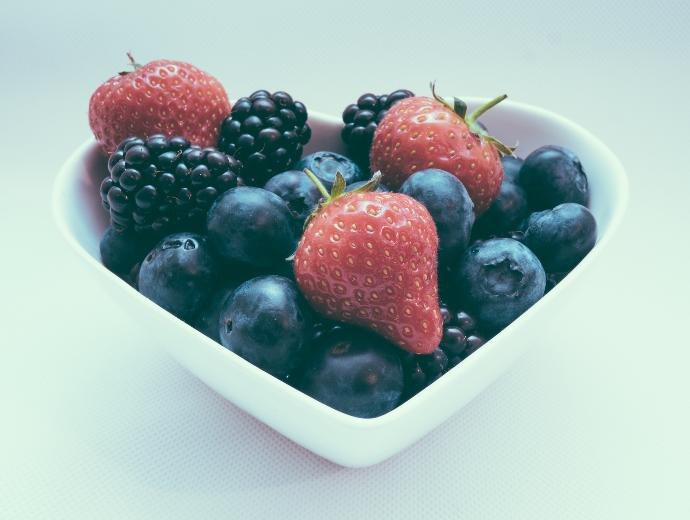 Uma tigela em forma de coração cheia de frutas vermelhas